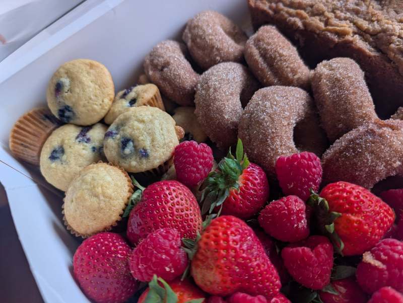 Brunch box with mini blueberry muffins, cinnamon-sugar donuts, and fresh strawberries and raspberries